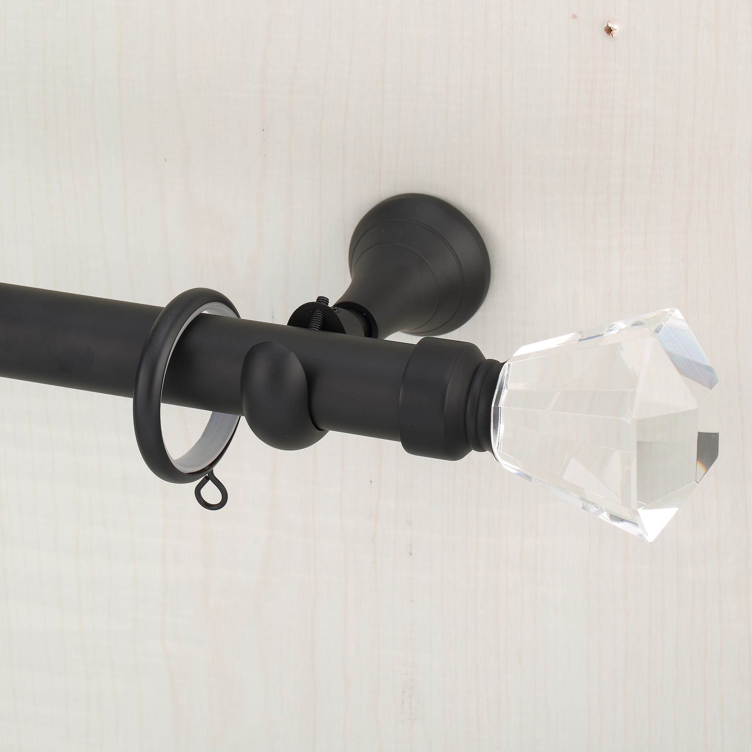 Black curtain rod with crystal finial on a white background